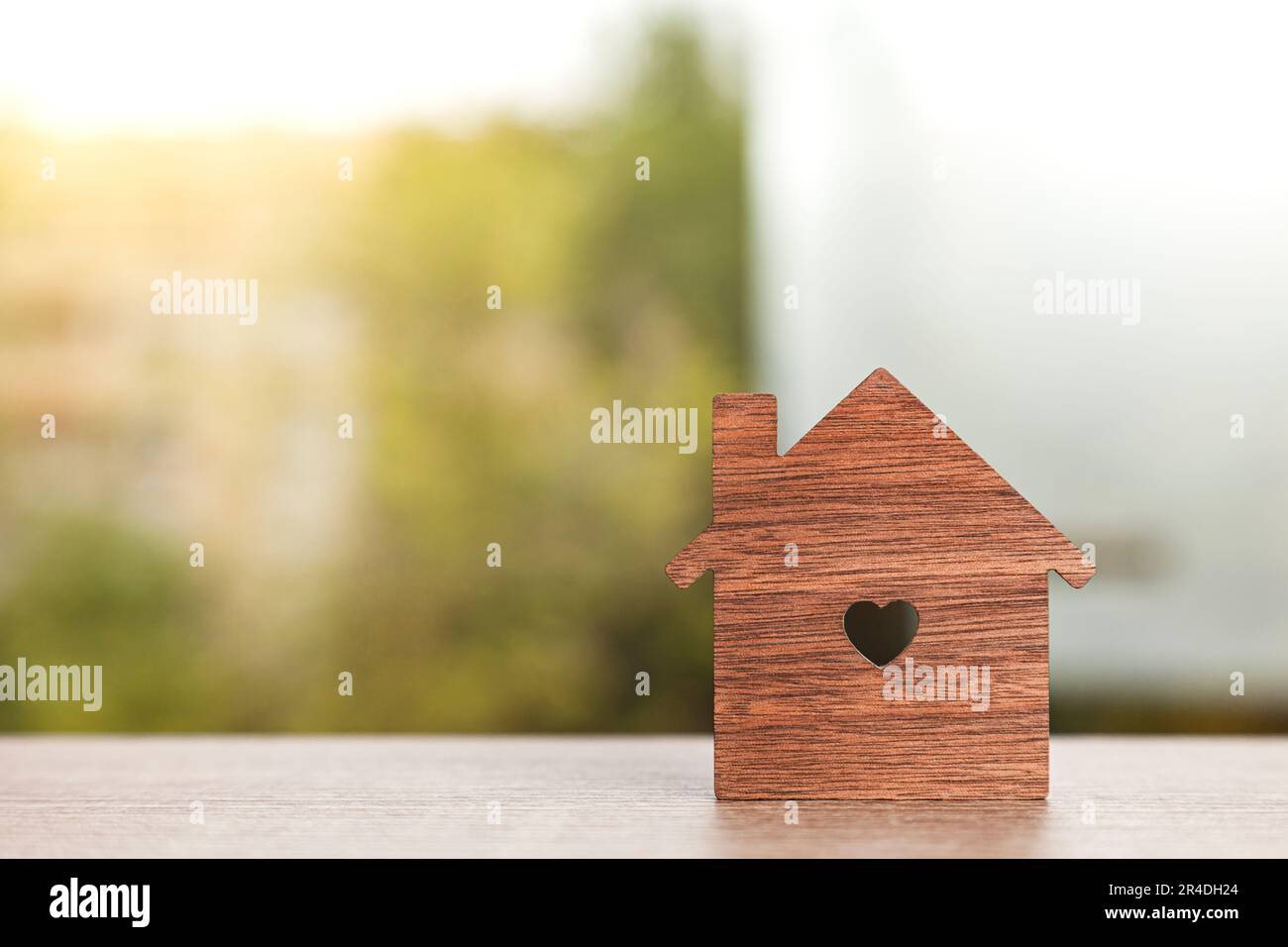 Gros plan horizontal d'une silhouette en forme de maison avec un trou en forme de coeur au centre sur une table avec une fenêtre en arrière-plan Banque D'Images