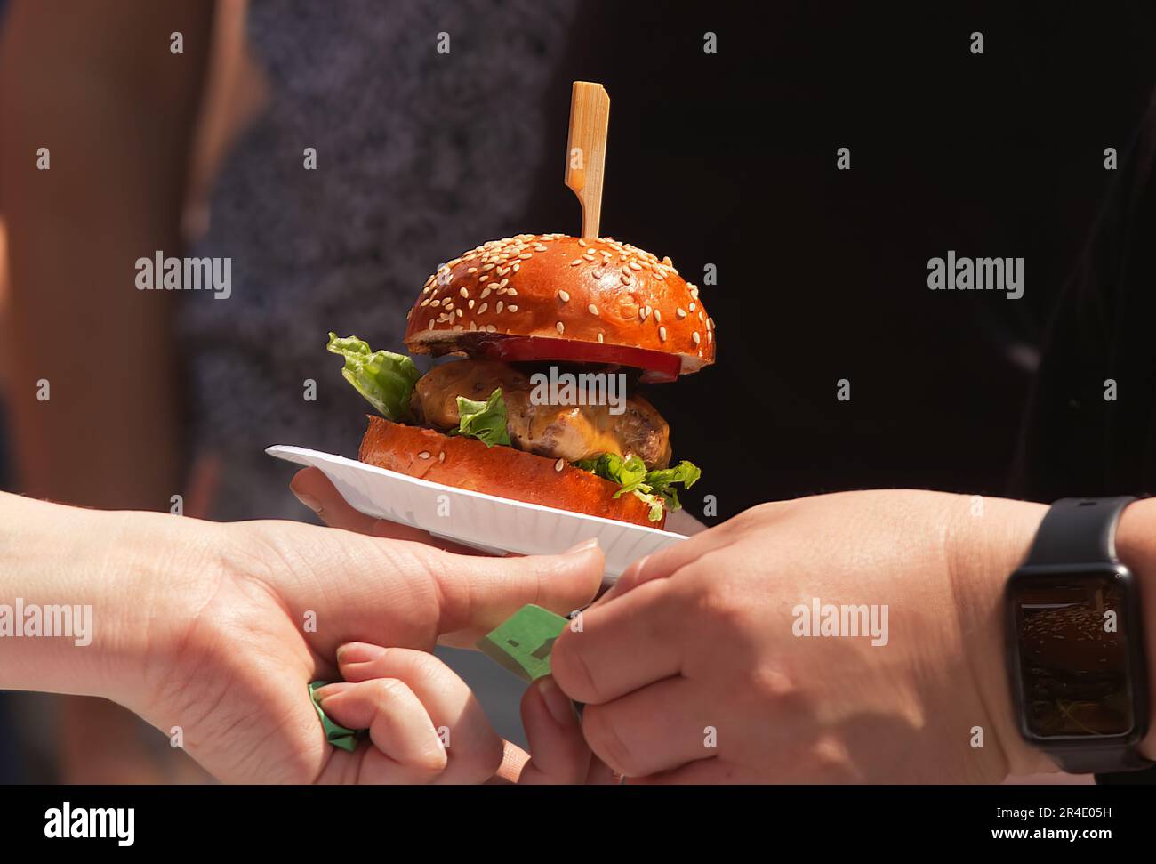 Vendre des hamburgers sur un marché de rue de fermiers. La cliente remet au préposé un bordereau de paiement et prend le hamburger sur un bac à papier Banque D'Images