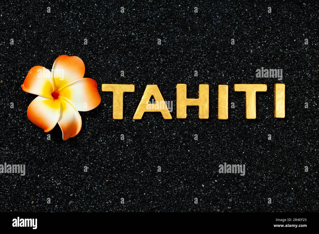 Tahiti - lettres d'or en sable noir et fleur de plumeria Banque D'Images