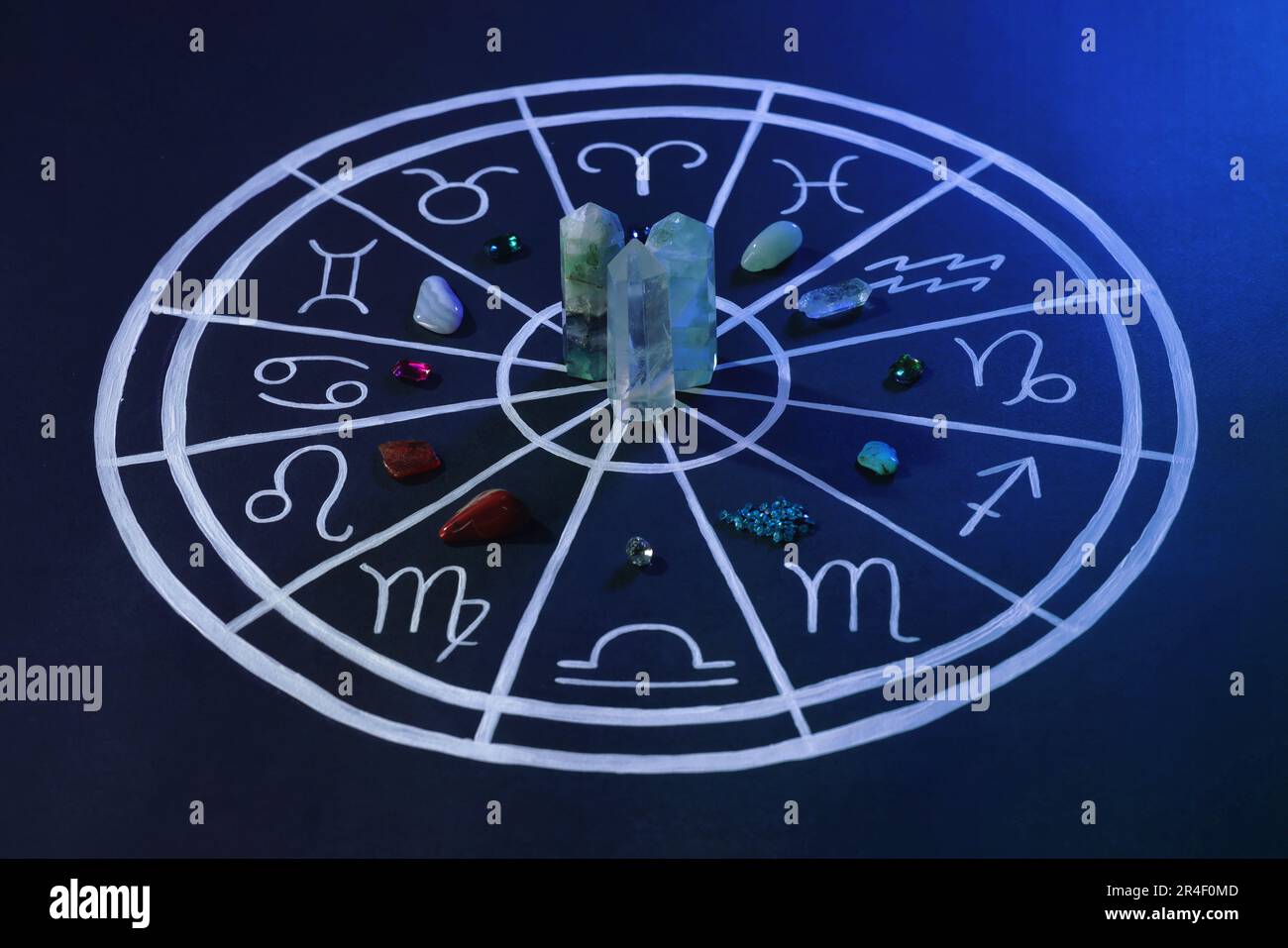 Pierres naturelles pour les signes du zodiaque et carte d'astrologie dessinée sur fond bleu foncé Banque D'Images