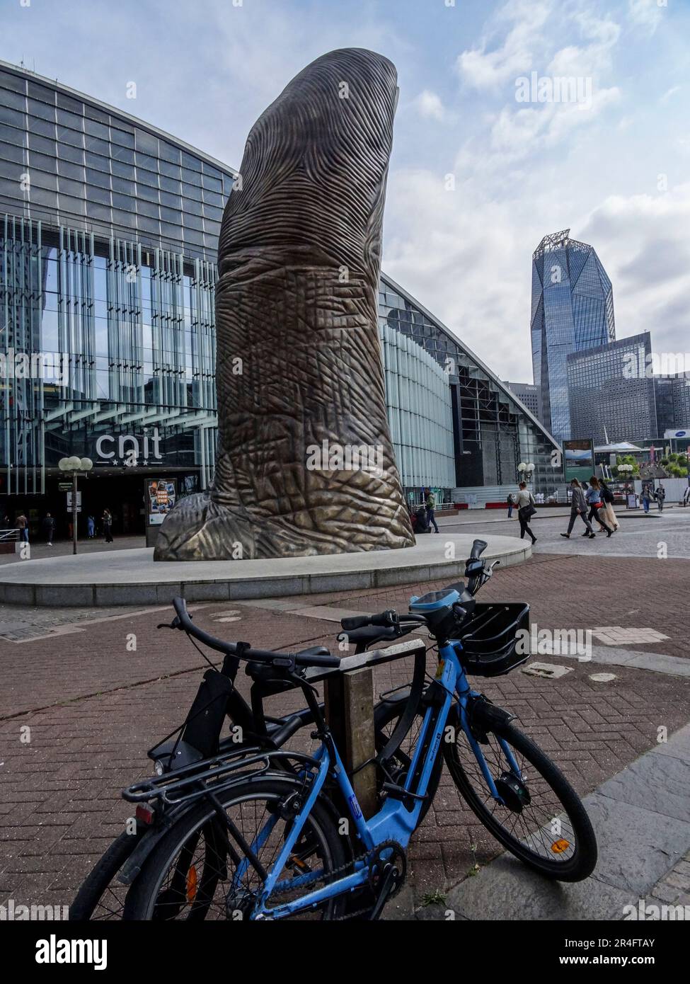 Vélos écologiques à Paris avec le pouce géant à la Défense au milieu du sol et architecture moderne derrière en fin d'après-midi soleil Banque D'Images