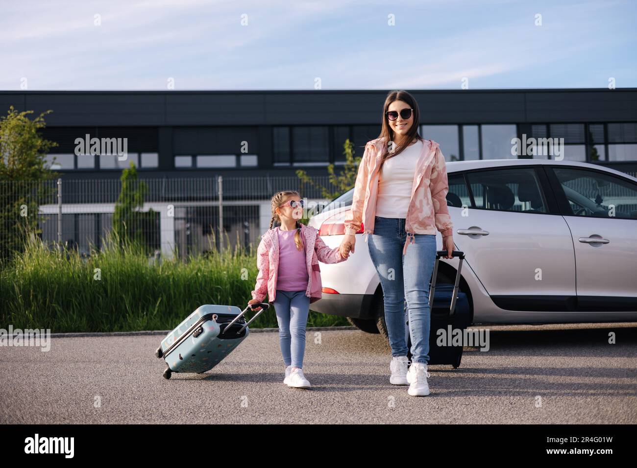 Une adorable fille avec sa mère va à l'aéroport avec des valises. Deux