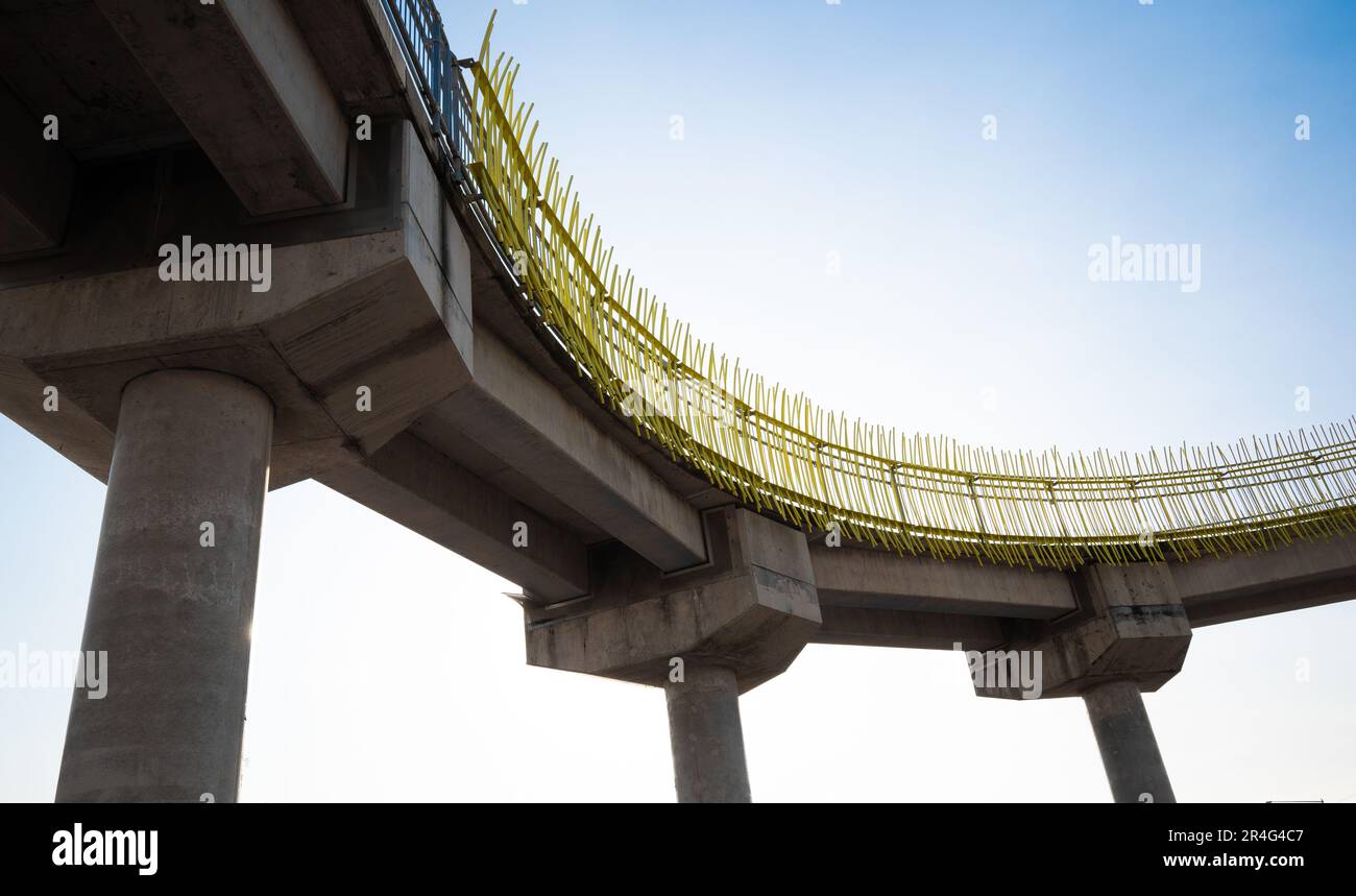 Photographie à angle bas d'une passerelle piétonne en béton avec rails en métal jaune, montrant des éléments d'ingénierie en béton robustes Banque D'Images