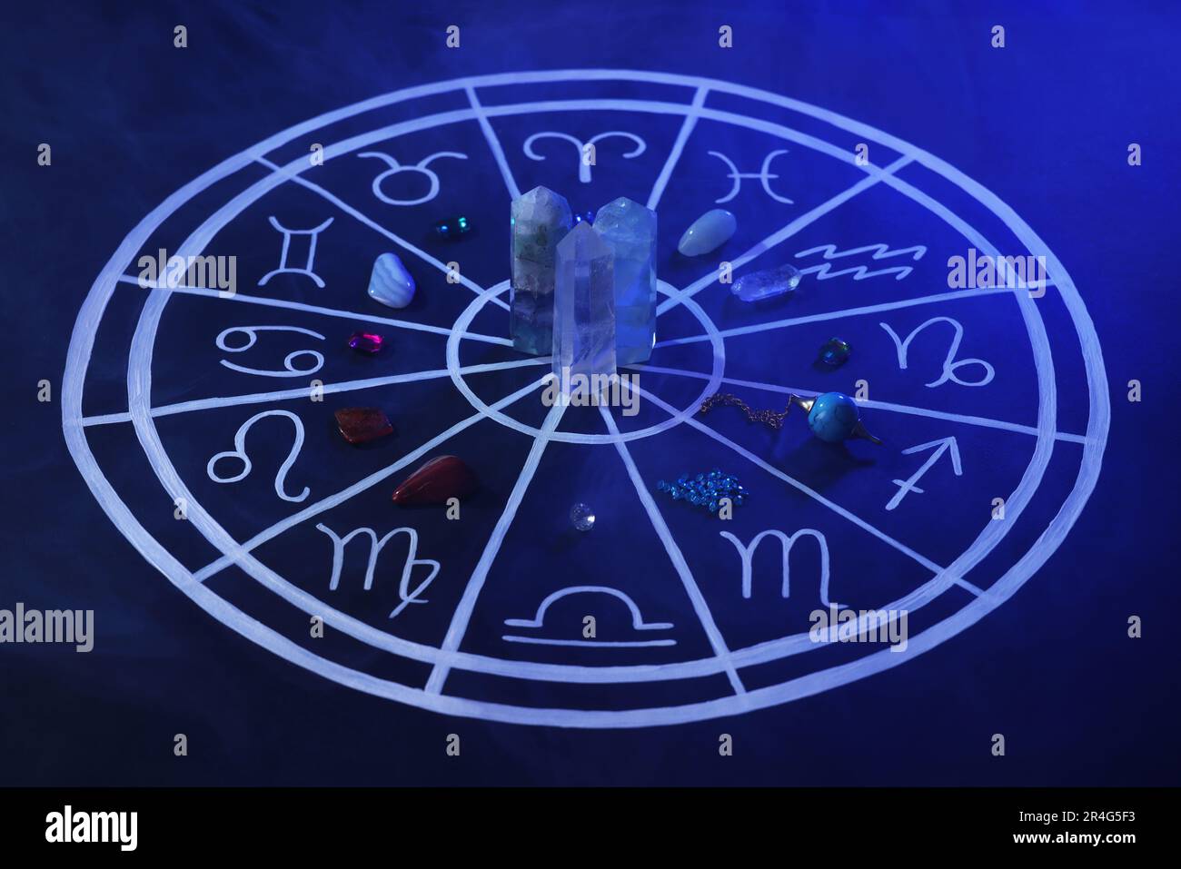 Pierres naturelles pour les signes du zodiaque et carte d'astrologie dessinée sur fond bleu foncé Banque D'Images