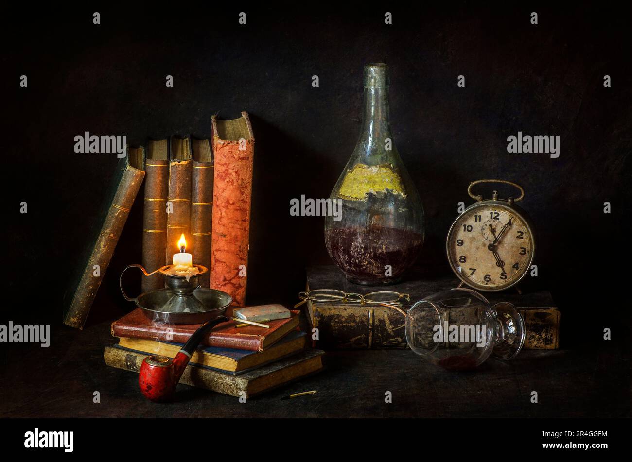 Classique encore vie avec des livres vintage placés avec une vieille bouteille de vin, horloge, verre de vin, pipe et bougie illuminée vintage sur fond rustique sombre Banque D'Images