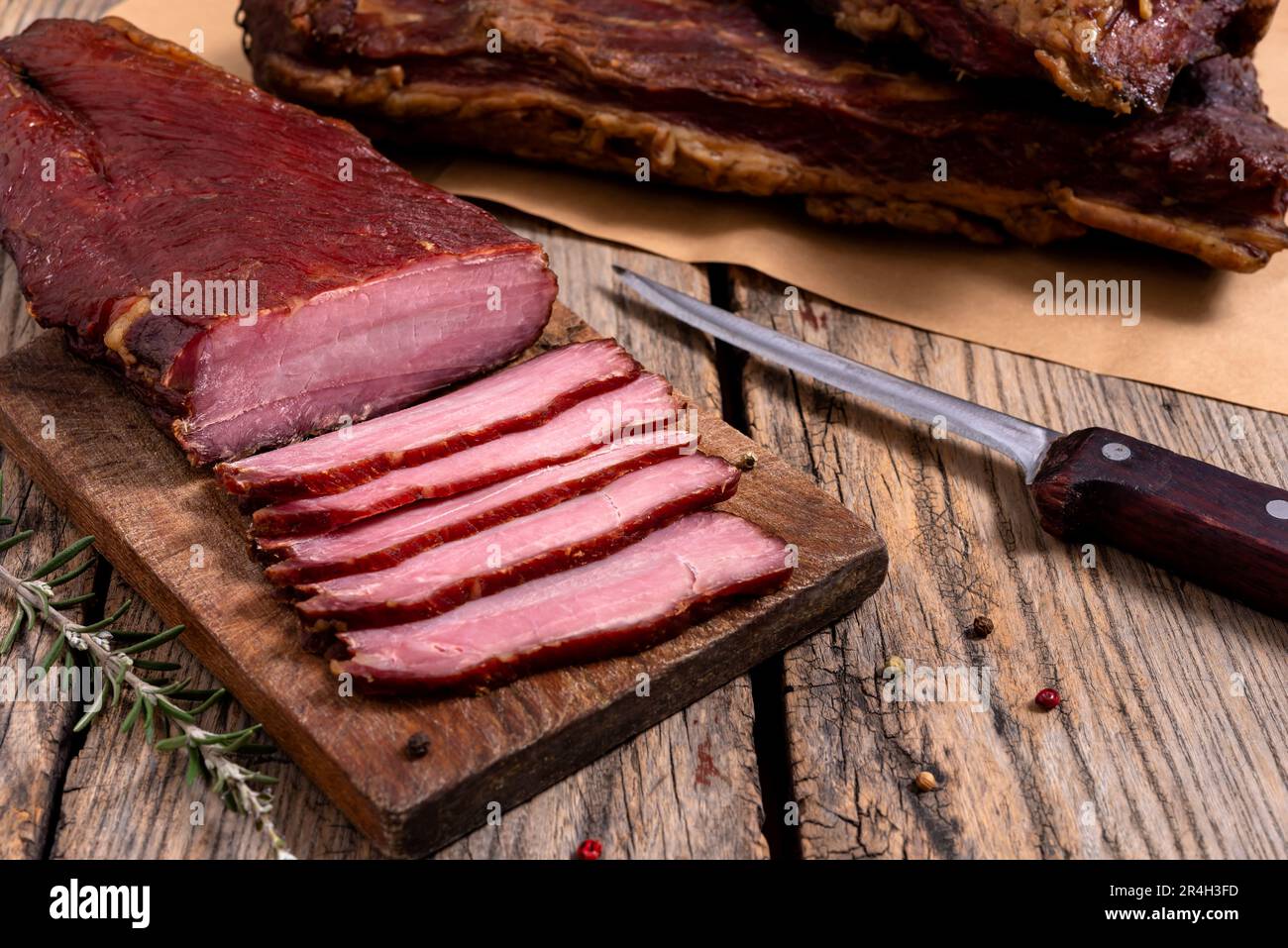 Planche à découper avec de la viande séchée, des épices et un couteau de cuisine sur une table en bois. Mise au point sélective. Banque D'Images