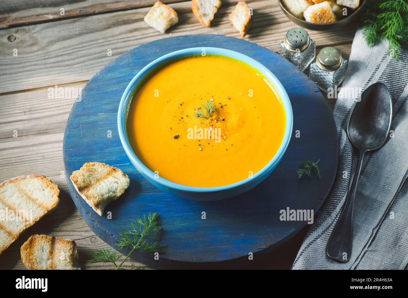 Soupe de pommes de citrouille rôtie servie avec du pain rôti et recouverte d'une saupoupe de poivre noir fraîchement moulu Banque D'Images