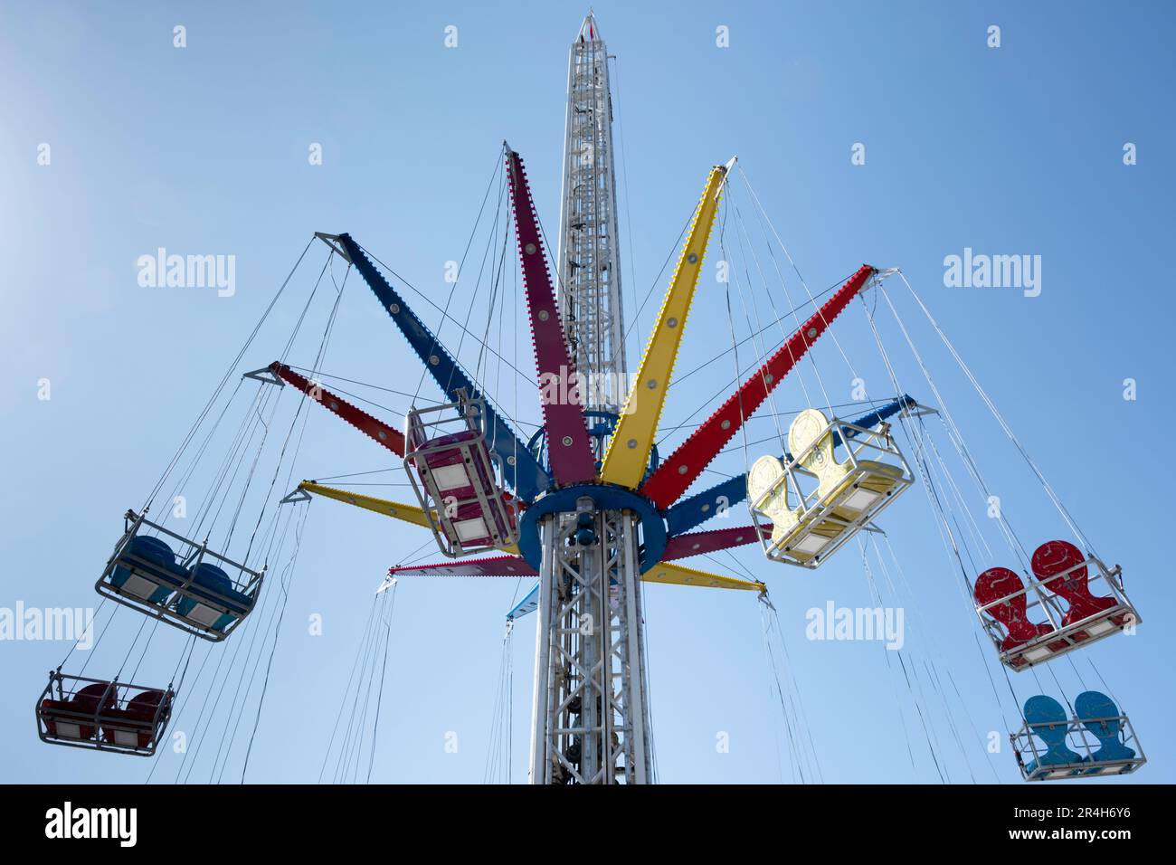 Manège à vide moderne, Wave Swinger ou Mega Whirlligig dans un parc d'attraction contre un ciel bleu. La partie supérieure rotative du carrousel s'incline également Banque D'Images