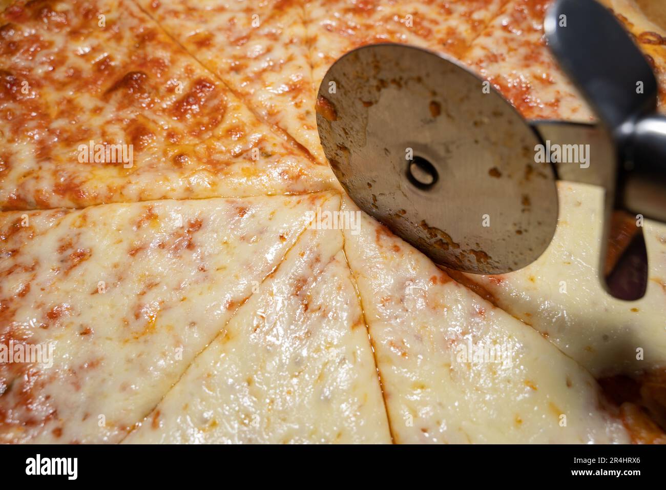 Pizza cuite et coupée en tranches margherita avec trancheuse à pizza en gros plan Banque D'Images