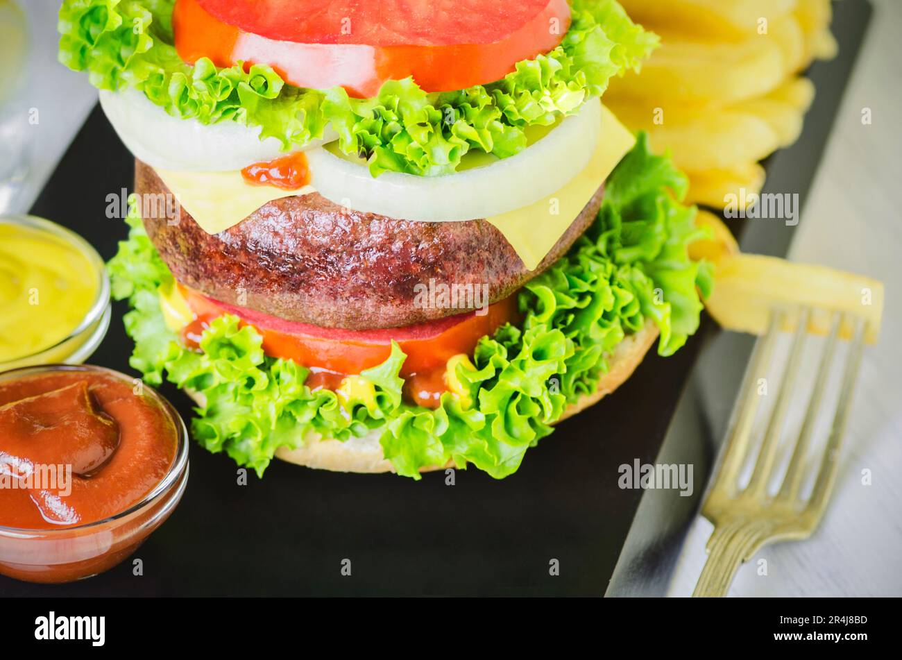 Délicieux hamburger de bœuf grillé géant, grand hamburger classique épais avec frites et légumes frais. Banque D'Images