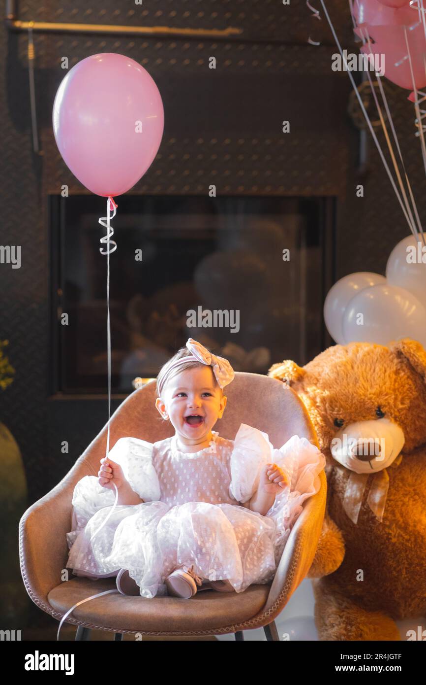Portrait d'une belle petite fille d'un an dans sa robe d'anniversaire tenant un ballon Banque D'Images