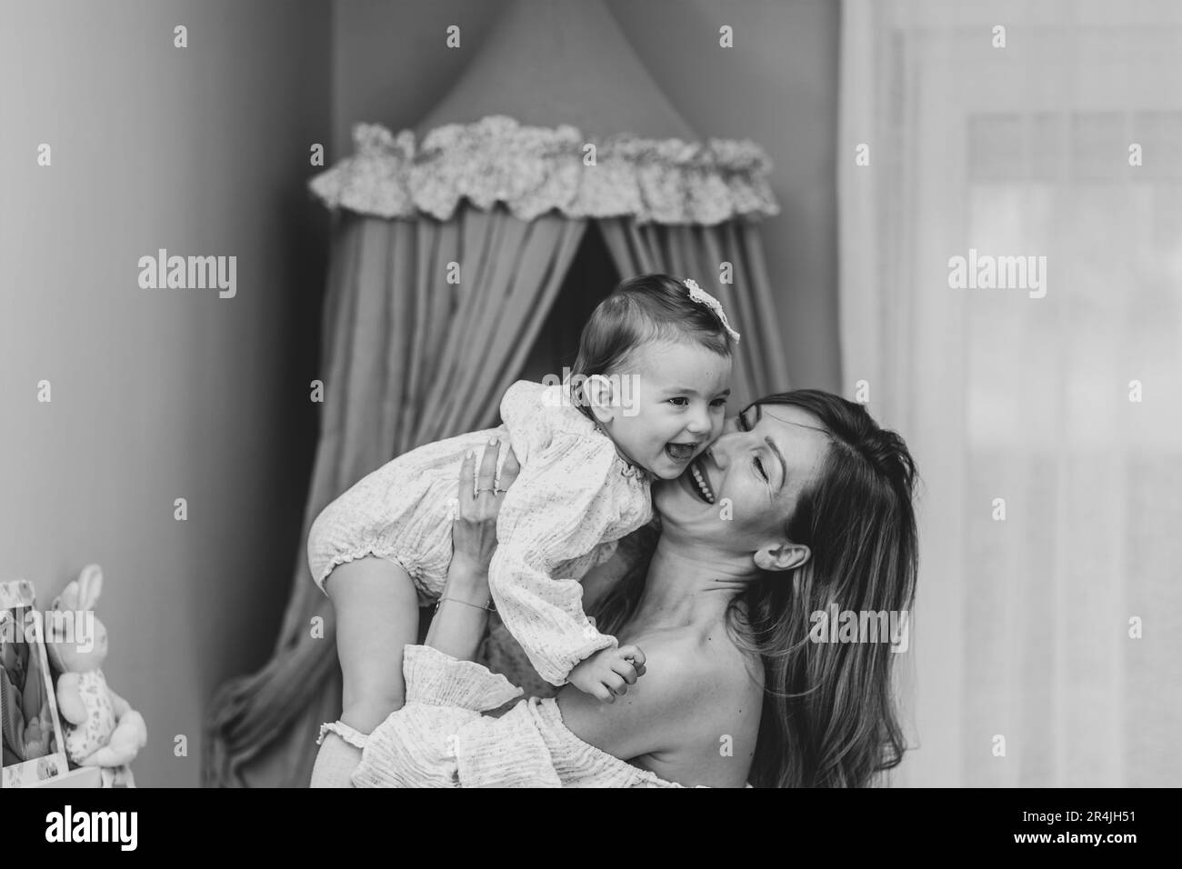Photo en noir et blanc d'une jeune blonde, élégante mère tenant sa petite fille, l'air levant Banque D'Images