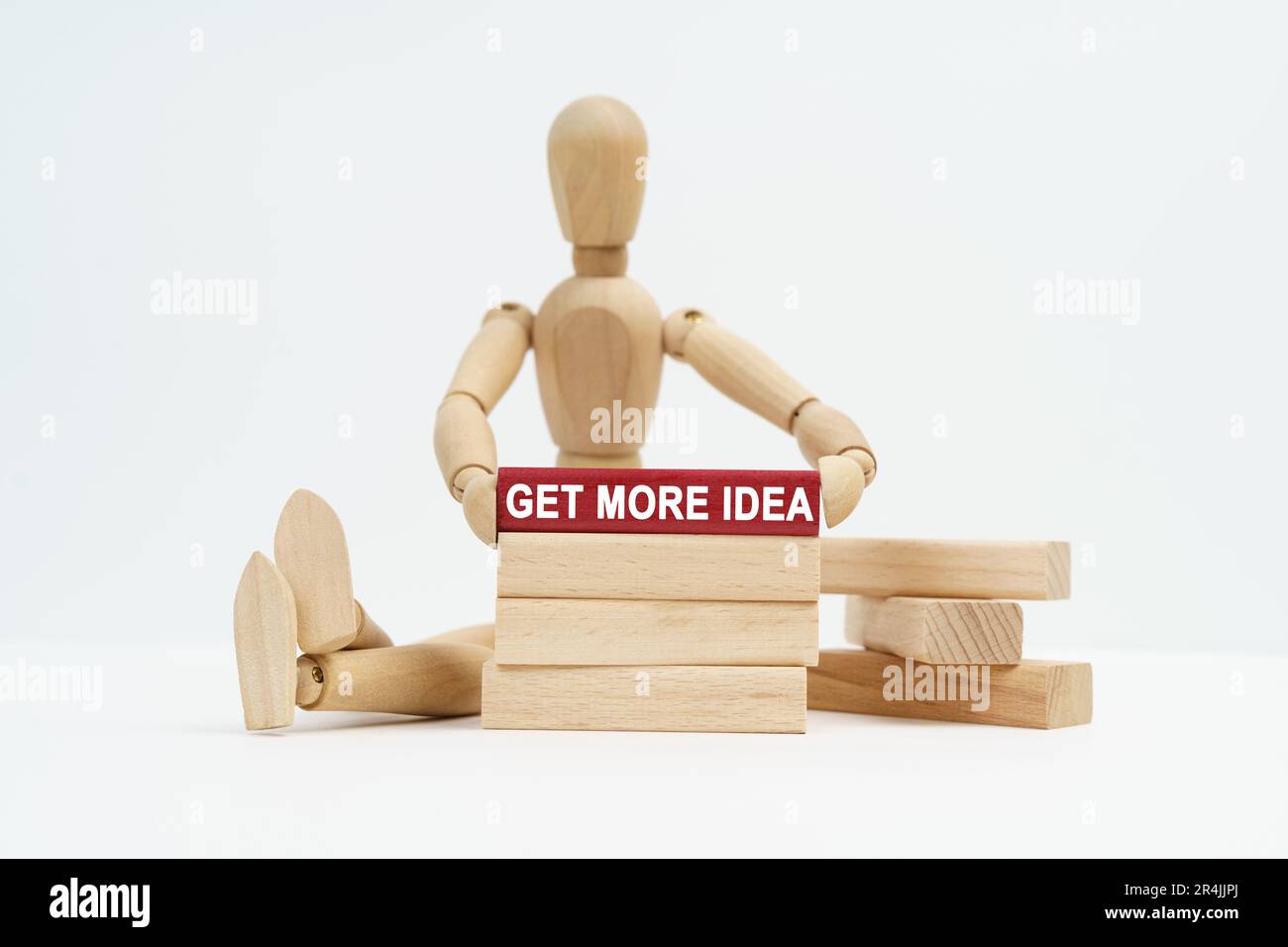 Concept d'entreprise. Sur une surface blanche se trouve un homme en bois dans ses mains un bloc avec l'inscription - obtenir plus d'idée Banque D'Images