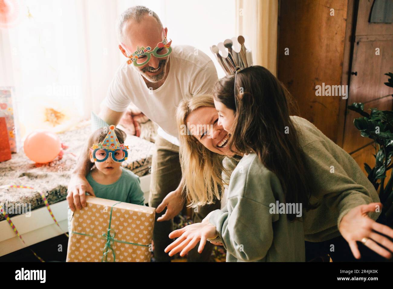 Joyeux parents et garçon donnant cadeau d'anniversaire à la fille à la maison Banque D'Images