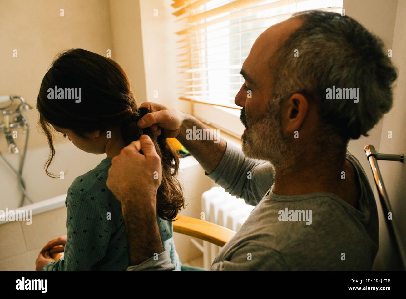Le père tressait les cheveux de sa fille dans la salle de bains Banque D'Images