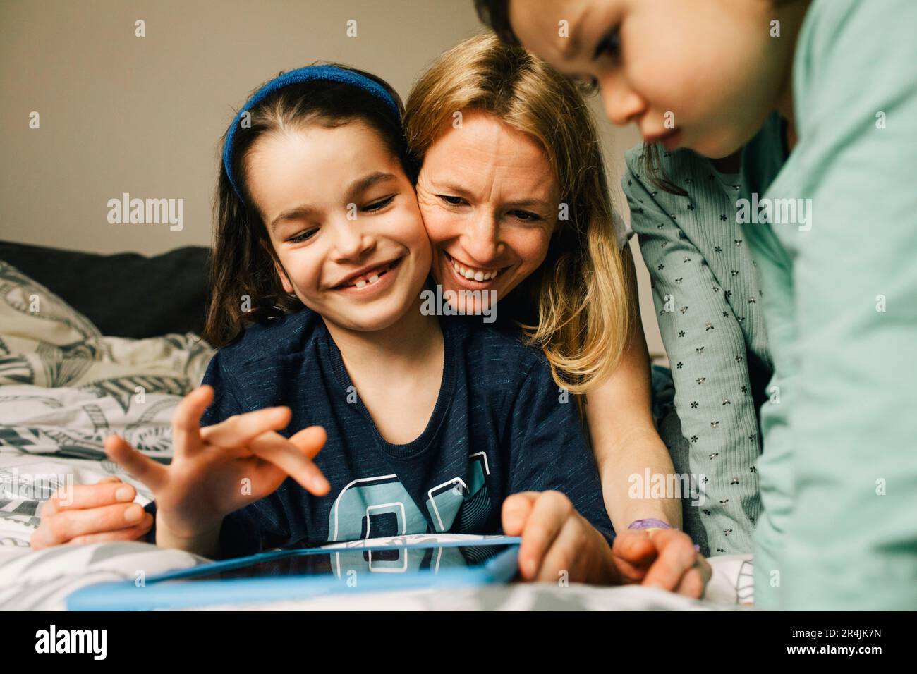 Une femme heureuse avec des fils utilisant une tablette numérique à la maison Banque D'Images