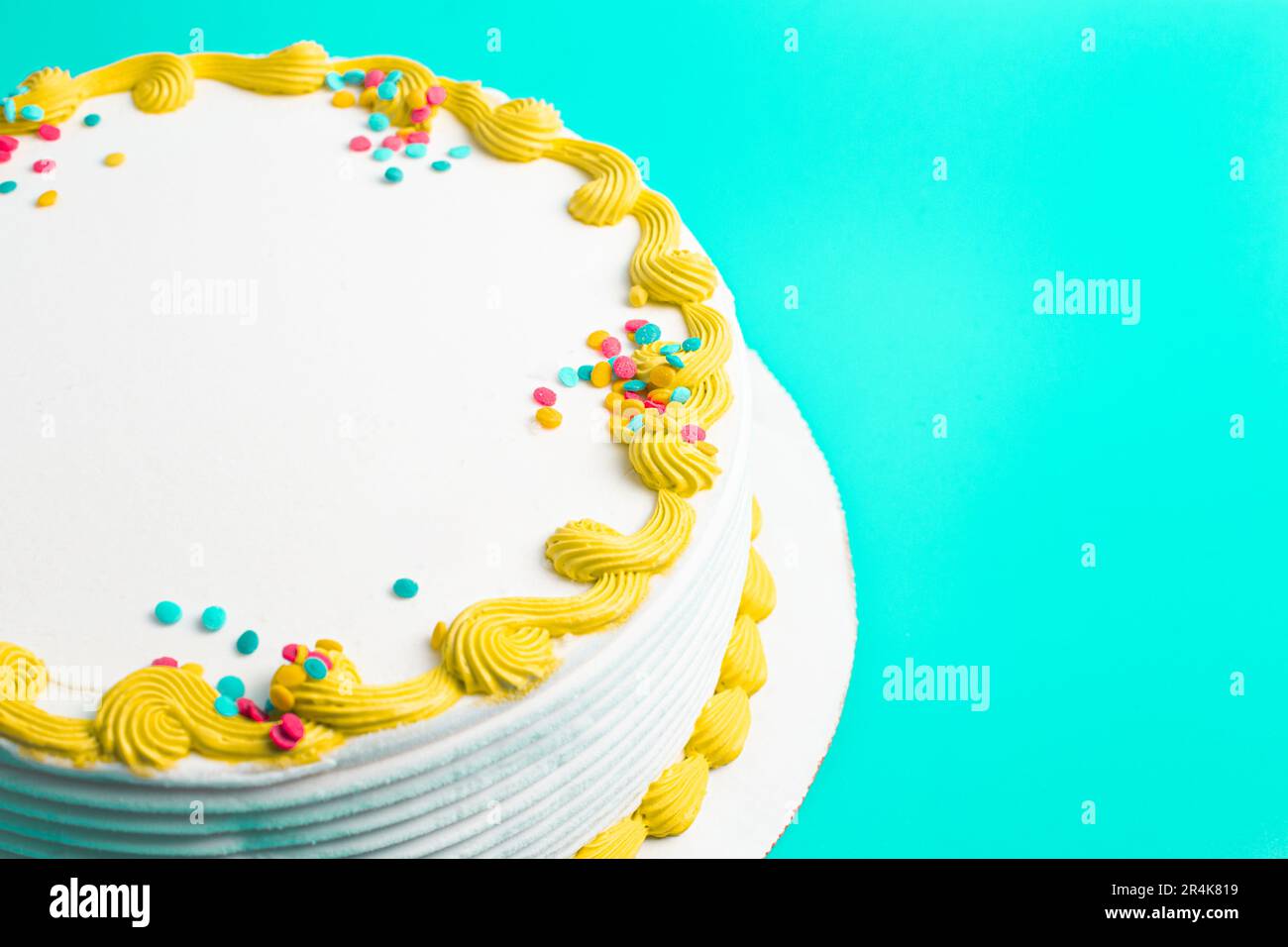Un gâteau circulaire à la crème glacée blanche avec bordure colorée et prprinkles Banque D'Images