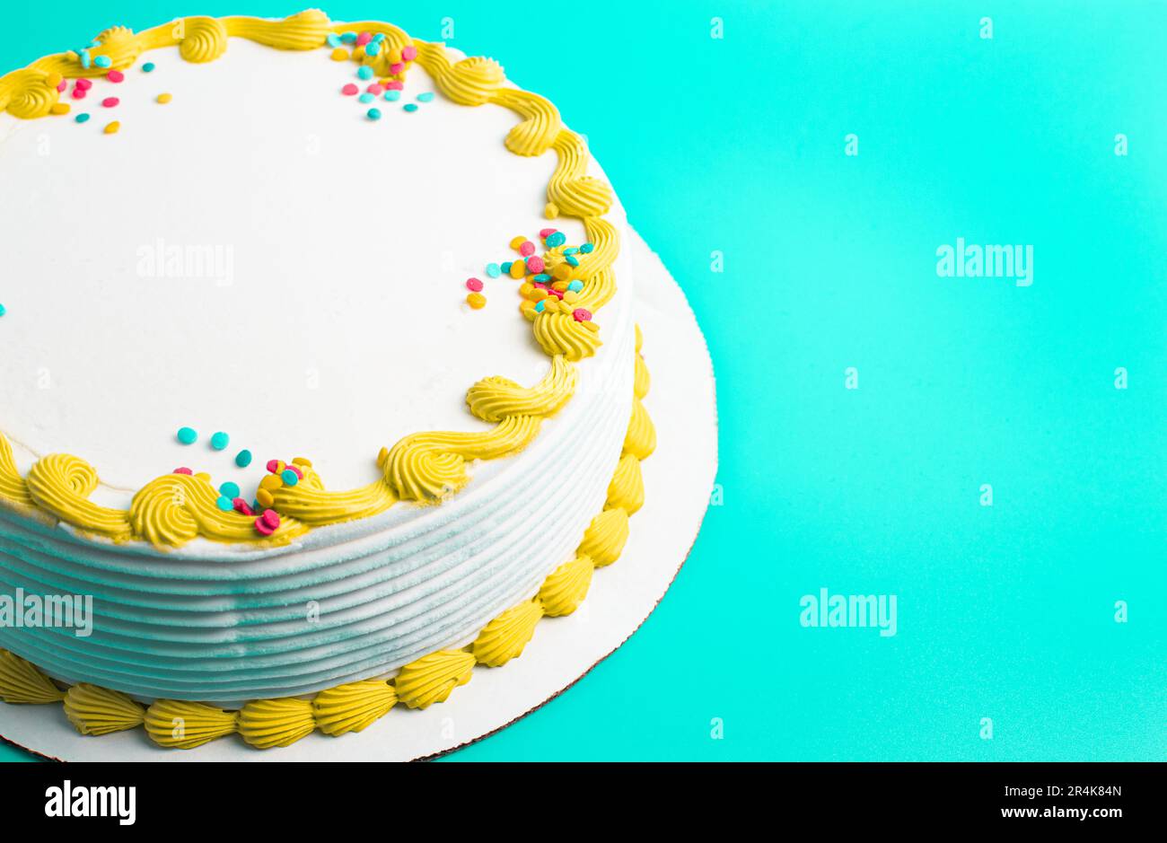 Un gâteau circulaire à la crème glacée blanche avec bordure colorée et prprinkles Banque D'Images