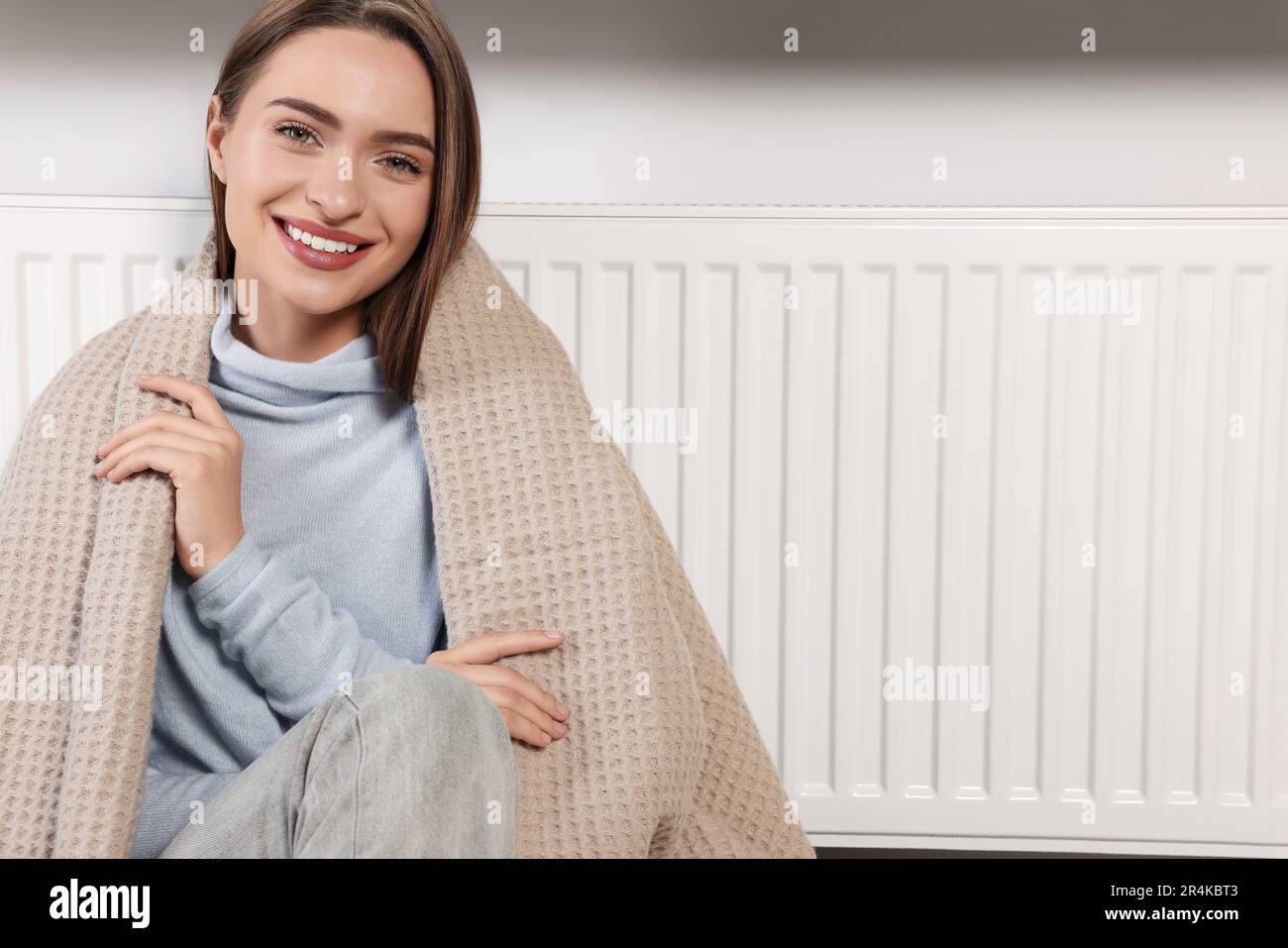 Femme avec une couverture près du radiateur de chauffage à l'intérieur,  espace pour le texte Photo Stock - Alamy