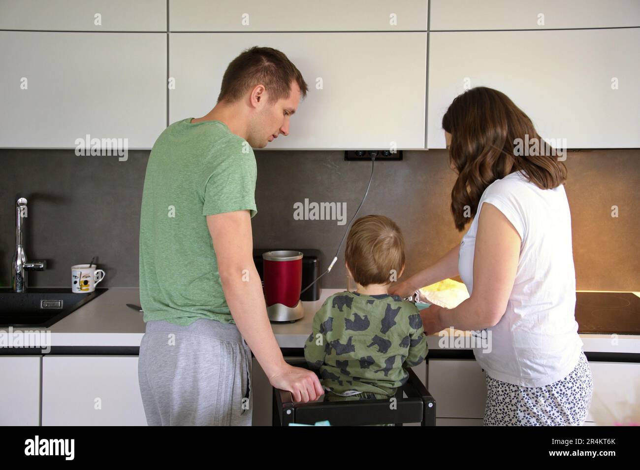 Tout-petit et ses parents cuisent ensemble dans la cuisine Banque D'Images