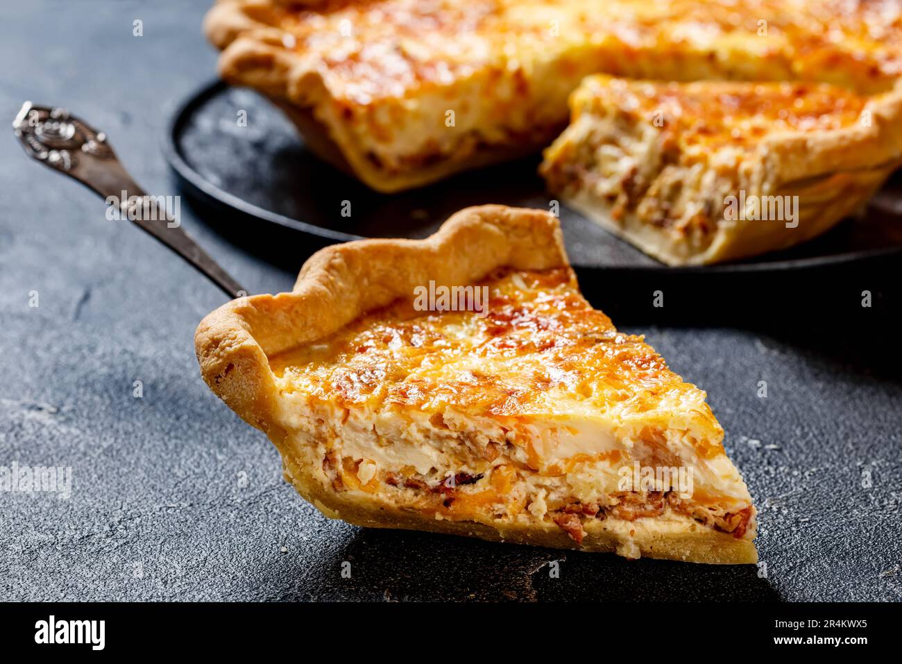 gros plan d'une quiche de petit déjeuner moelleuse avec garniture au fromage et au bacon sur une pelle à gâteau Banque D'Images