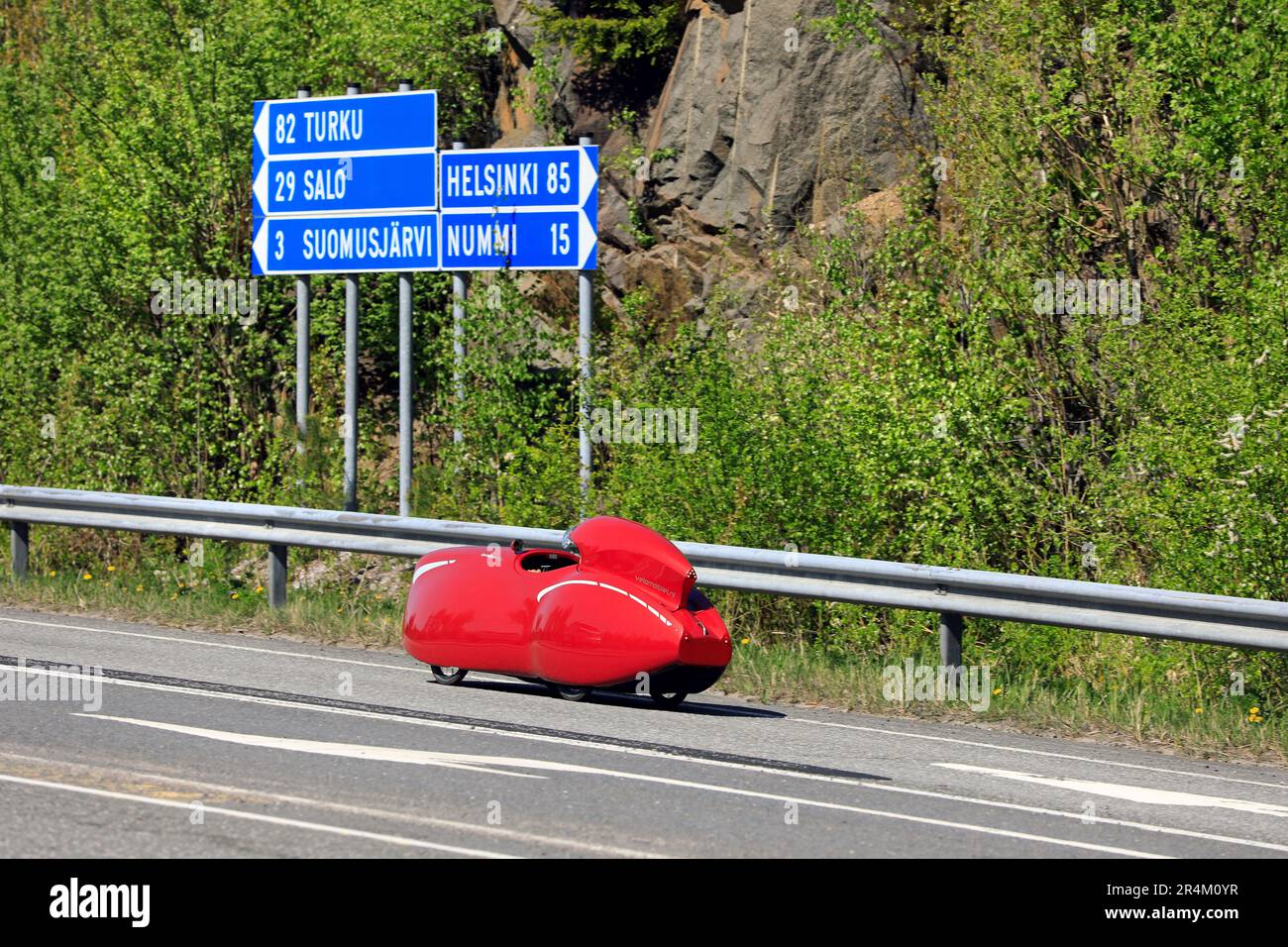 Voyage avec Velomobiel à quatre roues rouge Quattrovelo velomobile sur l'autoroute 110, signalisation routière indiquant les distances. Salo, Finlande. 20 mai 2023. Banque D'Images