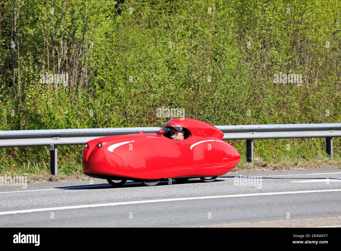 Cycliste à bord d'un Velomobiel rouge, à quatre roues et aérodynamique Quattrovelo velomobile le long de l'autoroute 110 à Salo, en Finlande. 20 mai 2023. Banque D'Images