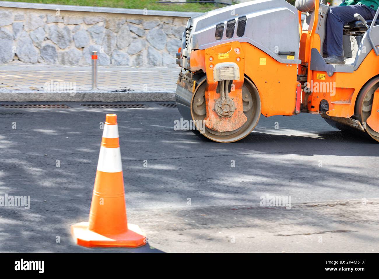 Un rouleau de construction dépose de l'asphalte frais sur la chaussée pour refaire surface de la route des voitures. Banque D'Images