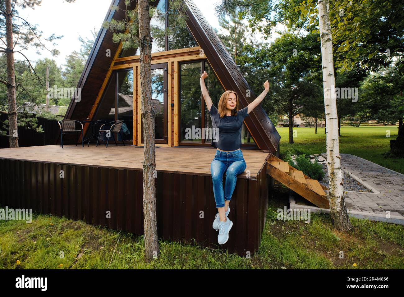 Femme dans une maison de campagne assise sur la terrasse et jouit d'une vue magnifique et de l'air frais Banque D'Images