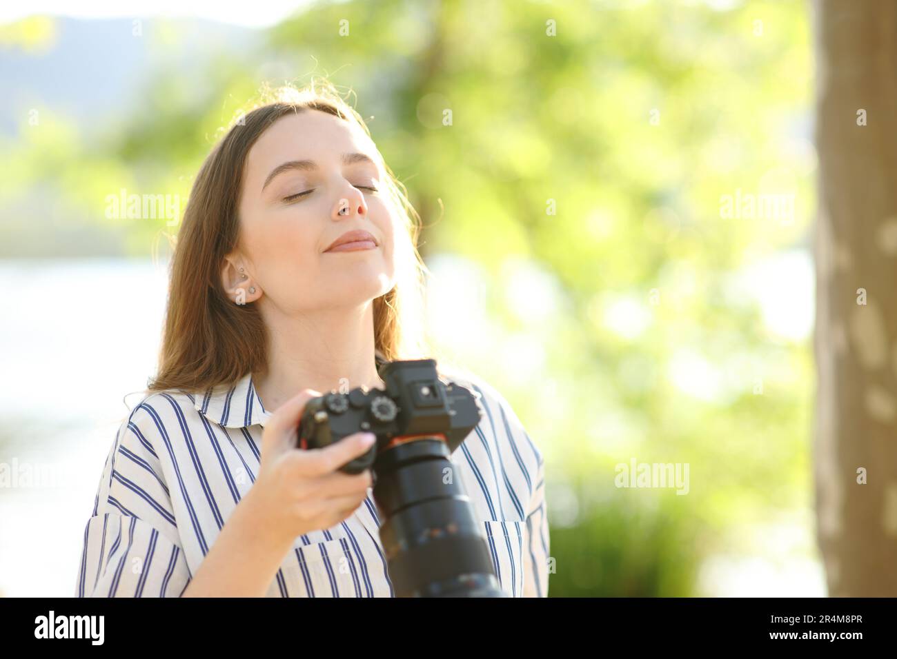 Photographe respirant de l'air frais tenant un appareil photo sans miroir dans la nature Banque D'Images