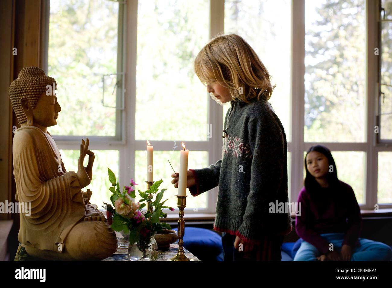 Un garçon allume l'encens dans un alter lors d'une retraite familiale bouddhiste sur l'île de Vashon, Washington. Banque D'Images