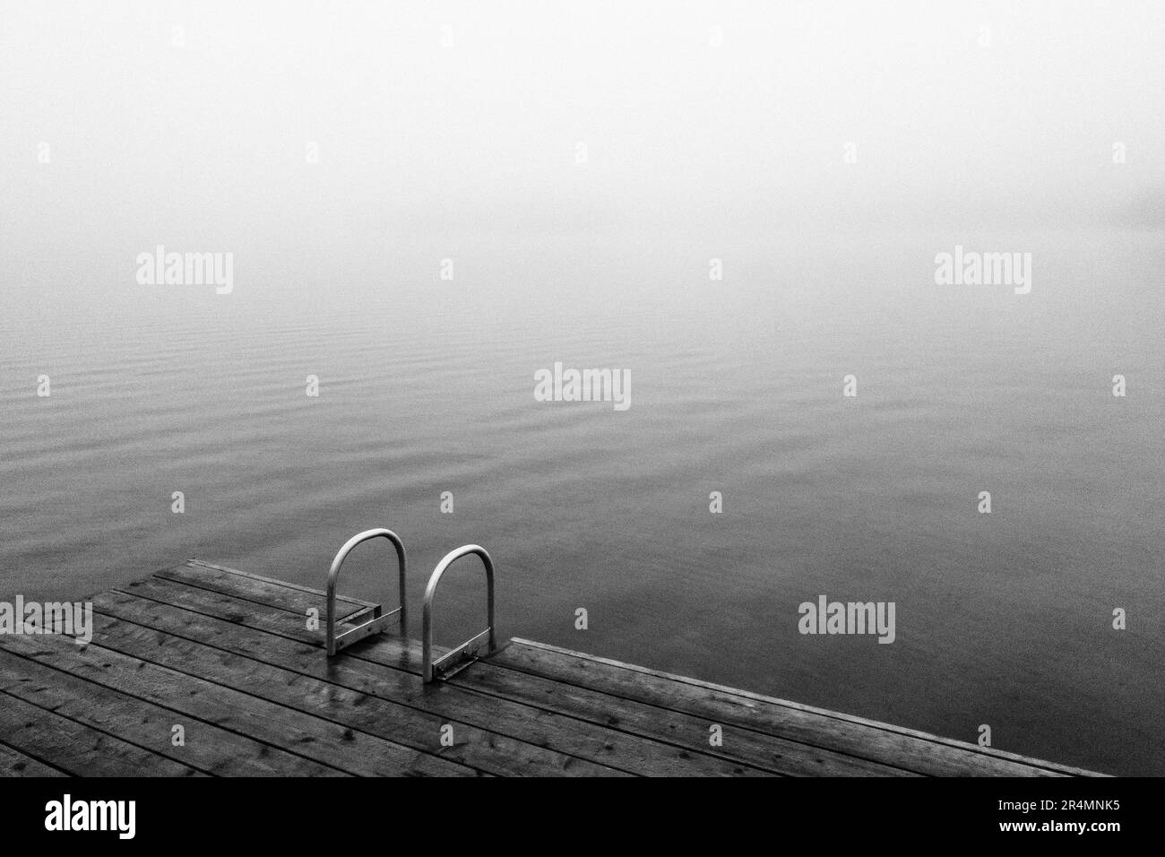 Photo en noir et blanc de Dock on Lake dans un climat de Hazy à la pluie Banque D'Images