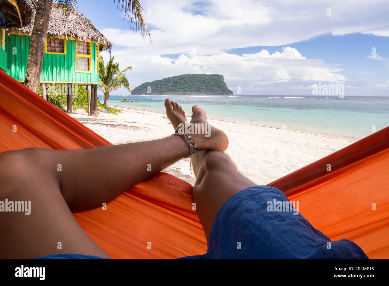 Les jambes de l'homme sur un hamac à la plage de sable tropical de Samoa Banque D'Images