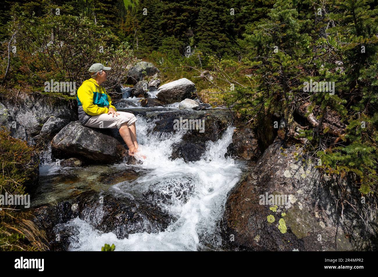 Vue sur toute la longueur des femmes rafraîchissants pieds fatigués dans une rivière alpine froide. Banque D'Images