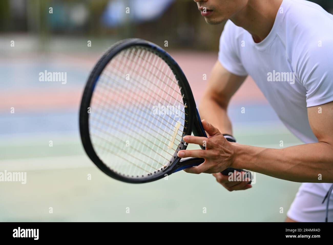Un joueur de tennis masculin s'est concentré en position de prêt pour recevoir un service, s'exerçant pour la compétition sur un court Banque D'Images