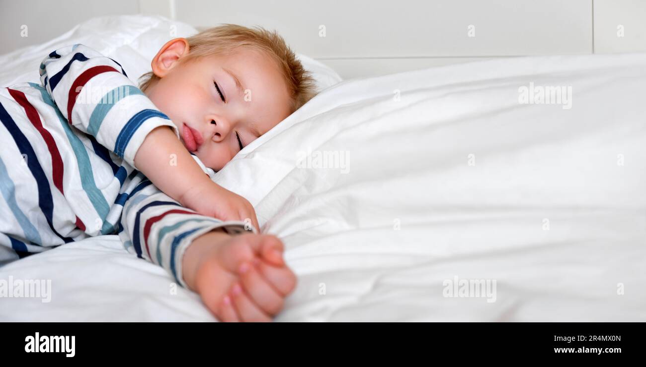 Enfant dormant dans le lit. Mignon petit enfant peut dormir sur une  couverture blanche confortable de son côté. Enfant de 2 ans dormant dans un  lit bébé. Gros plan sur la face.