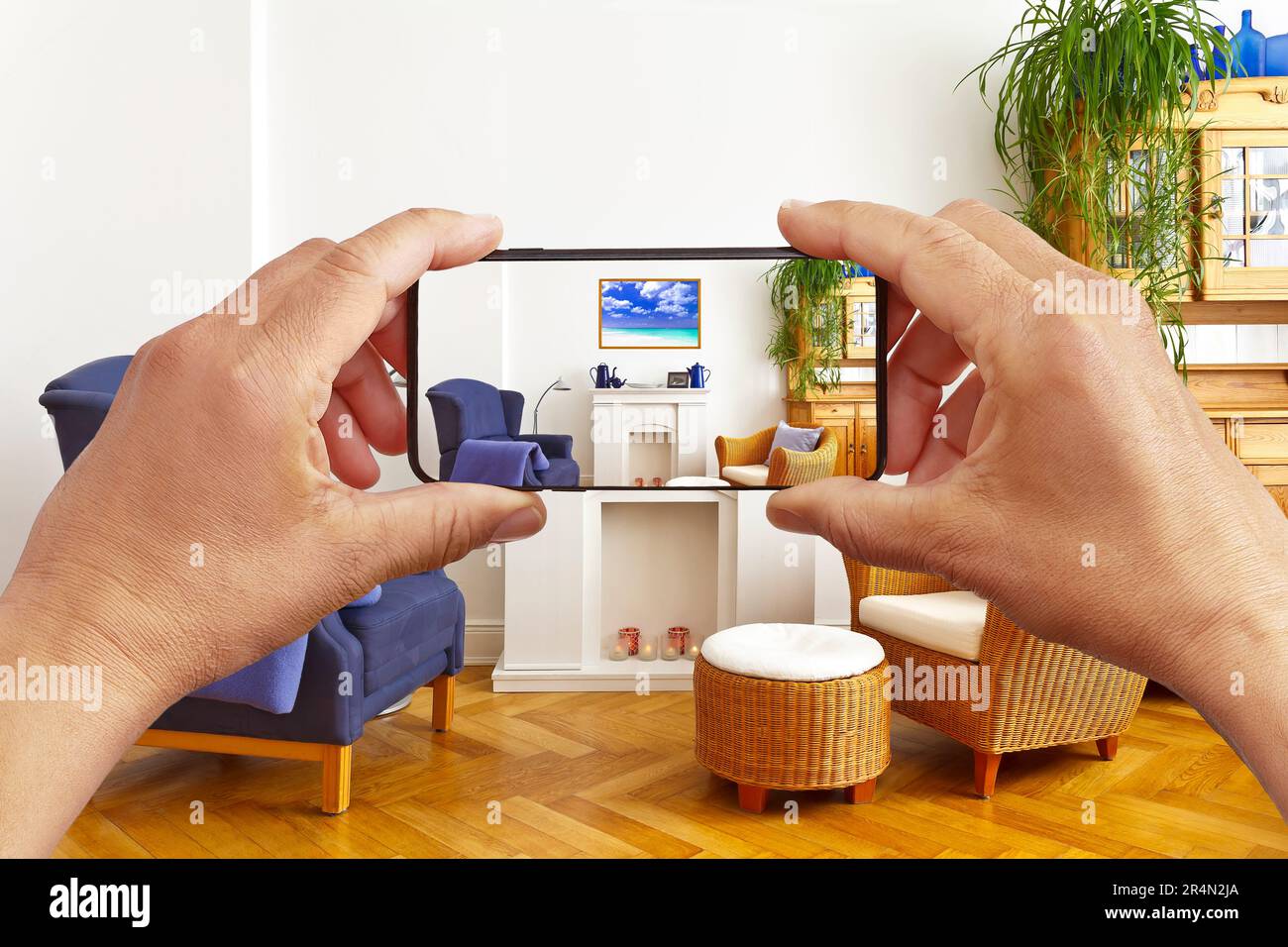 Concept de réalité augmentée : mains tenant le smartphone avec l'application de décoration intérieure AR, visualisant le salon avec un cadre photo supplémentaire. Banque D'Images