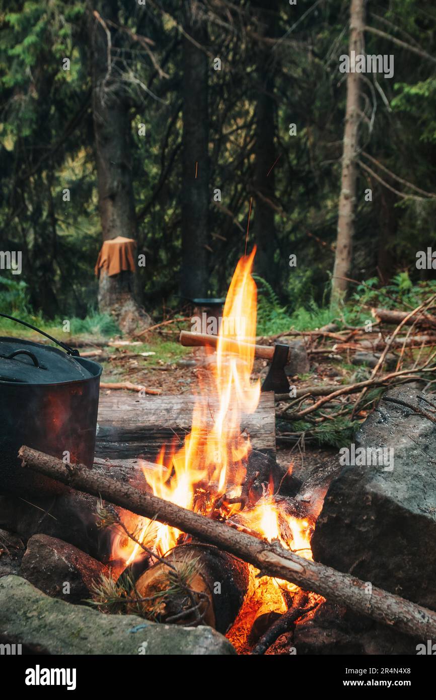 Feu de camp. Un chou-fleur de nourriture se trouve à proximité avec une hache en arrière-plan. Banque D'Images