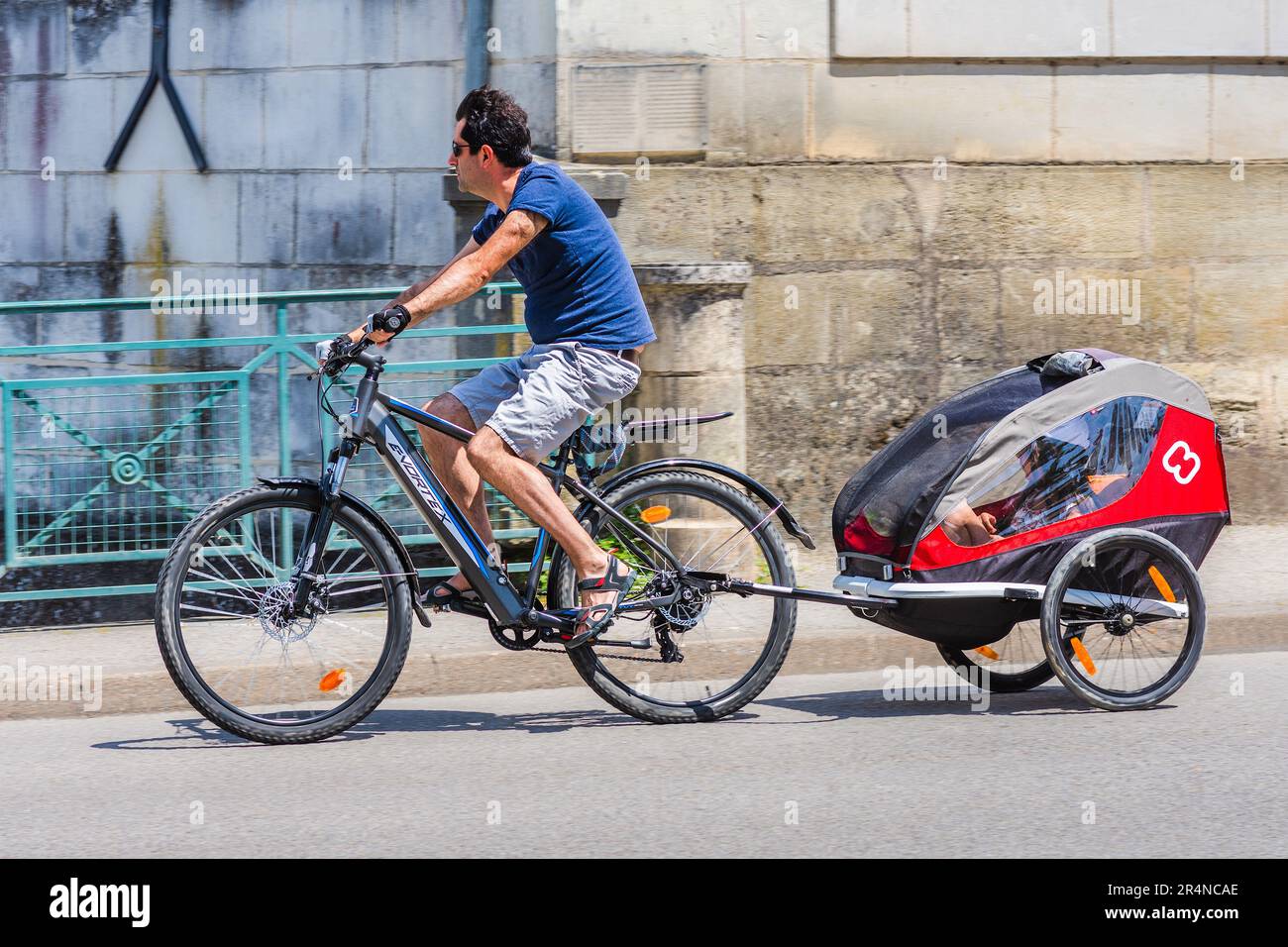 Homme sur E-Vortex vélo électrique avec deux enfants en remorque - Loches, Indre-et-Loire (37), France. Banque D'Images