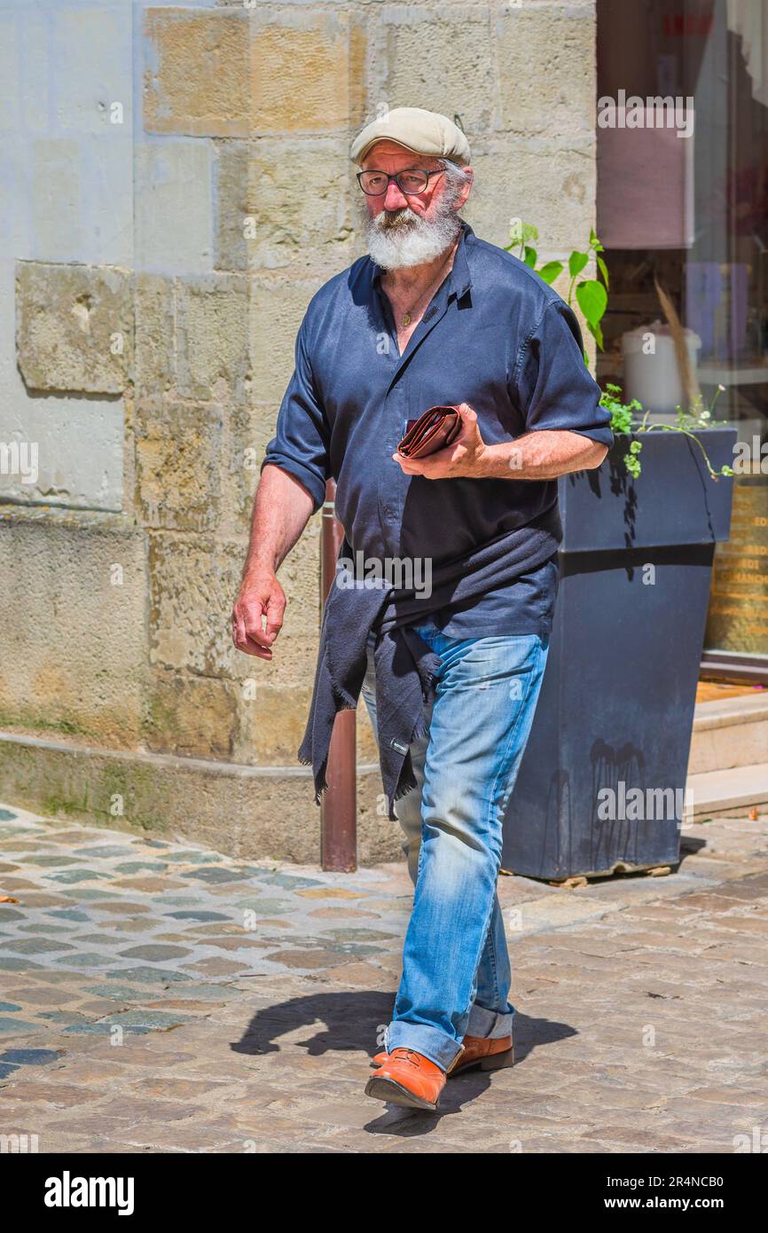 Homme barbu vêtu de façon décontractée qui marche le long de la rue de la ville - Loches, Indre-et-Loire (37), France. Banque D'Images