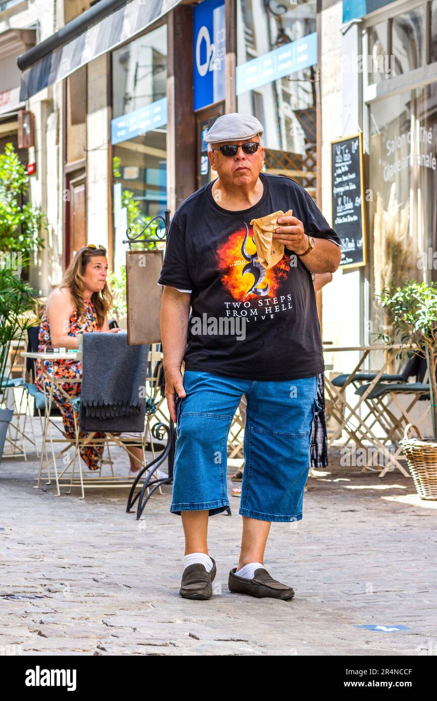 Roadie / scène main portant 'deux pas de l'Enfer' T-shirt manger snack dans la rue de ville - Loches, Indre-et-Loire (37), France. Banque D'Images