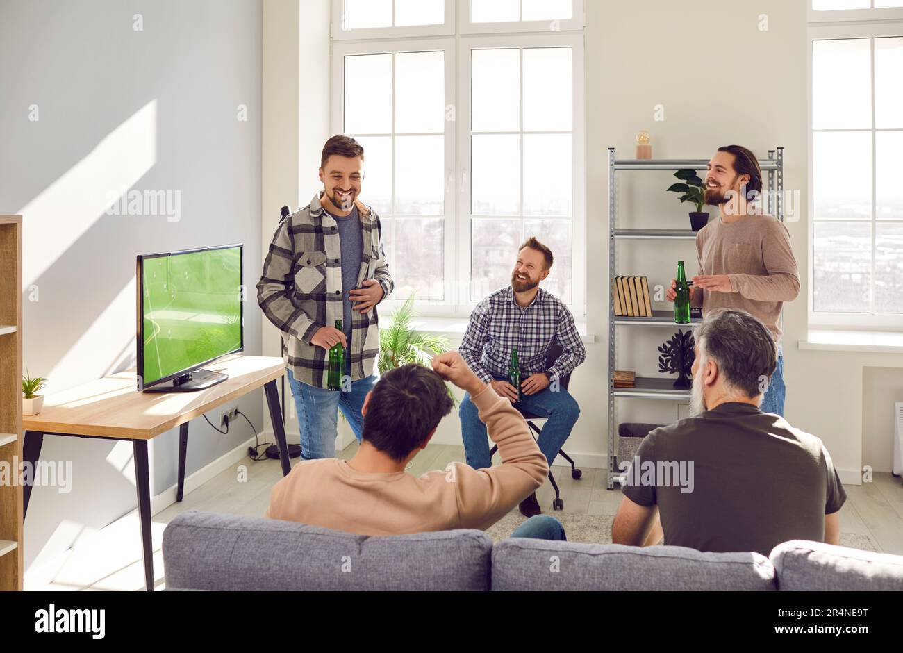 Groupe d'amis à barbe mûrs parlant pendant un match de football à la télévision à la maison avec de la bière. Banque D'Images