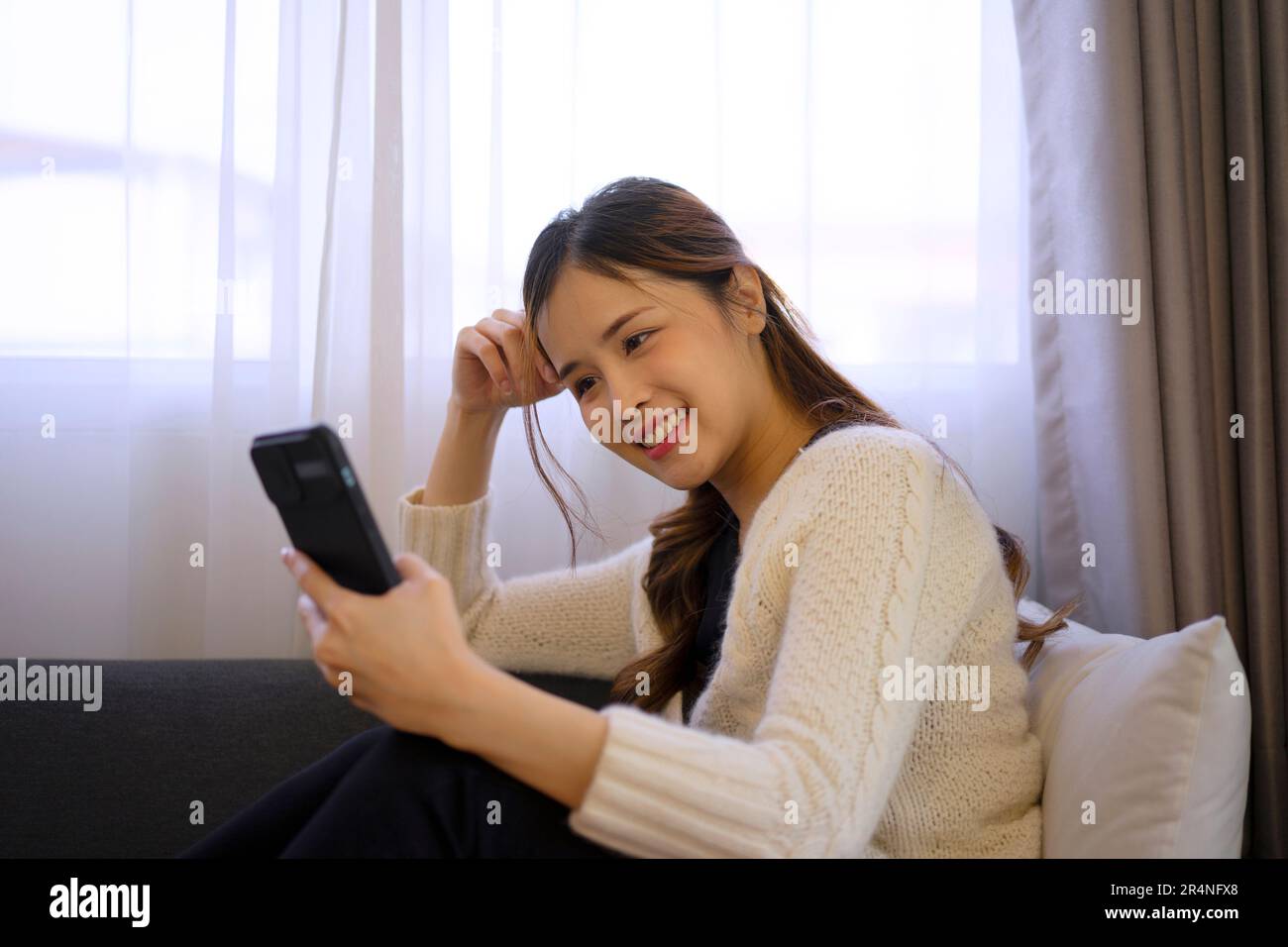 Jolie femme utilise un smartphone à la maison. Bonheur humeur, style de vie et concept technologique. Banque D'Images