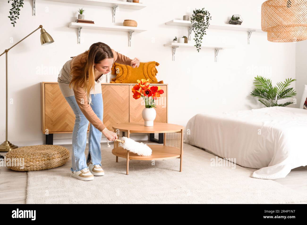 Une jeune femme nettoie la table avec un plumeau en pp dans la chambre  Photo Stock - Alamy