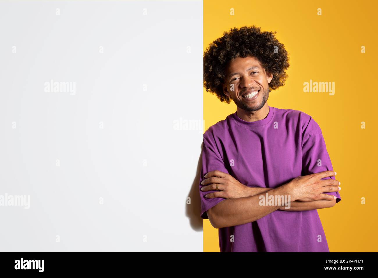 Positif mûr noir curly homme dans le t-shirt violet avec les bras croisés sur la poitrine avec banneur avec espace vide Banque D'Images