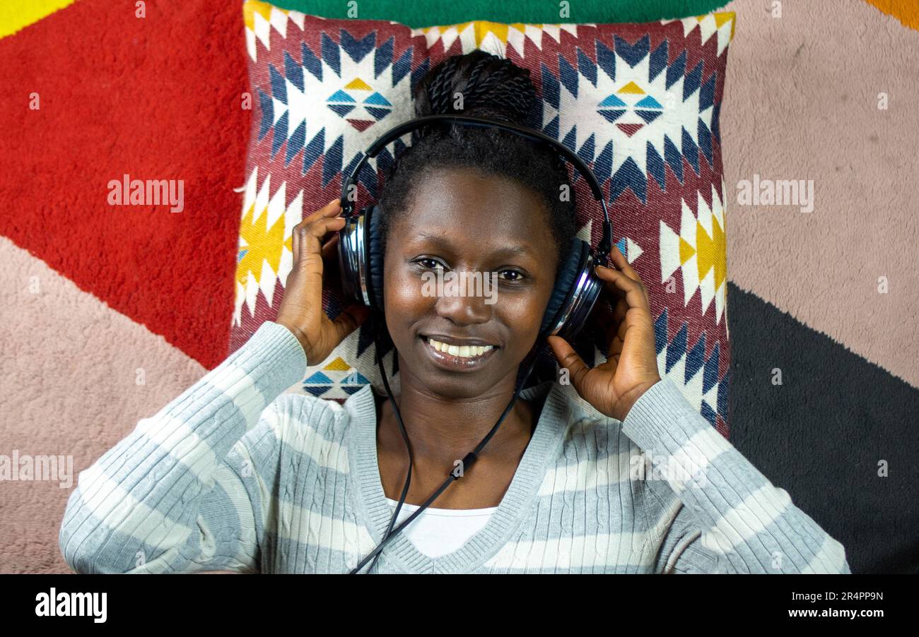 jeune femme utilisant un casque tout en étant couché sur un tapis coloré Banque D'Images