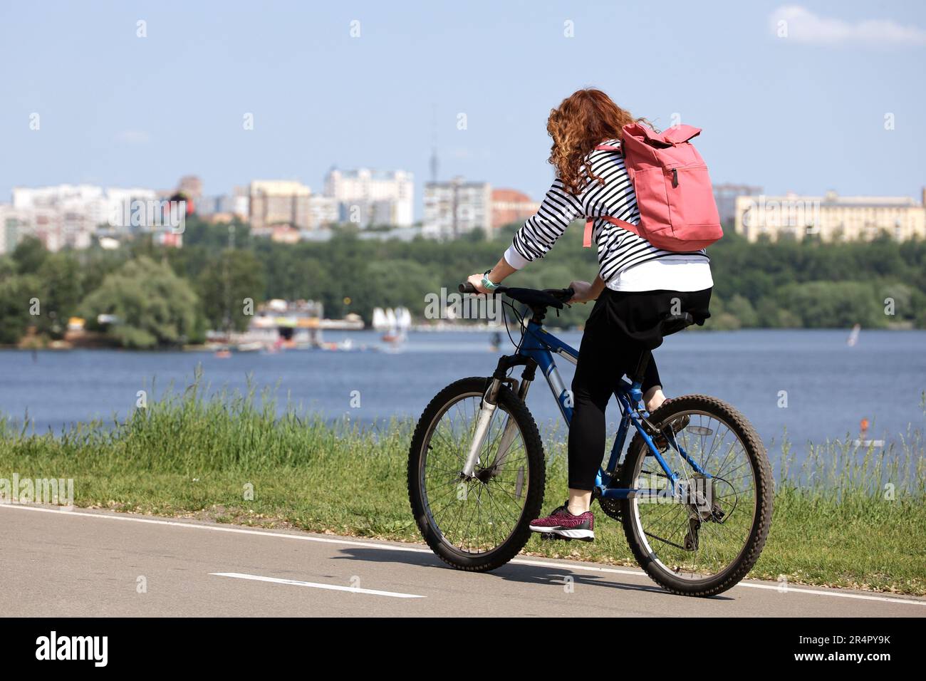 Femme touriste à vélo sur le fond de la rivière et du parc de la ville. Vélo et loisirs d'été Banque D'Images