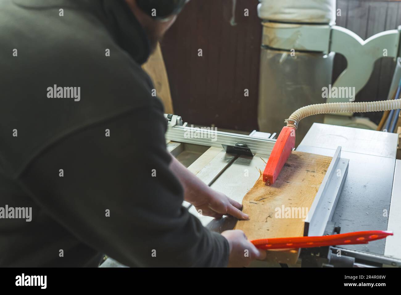 Charpentier en bois glissant sous la scie de table pour couper le bois en atelier de travail du bois. Photo de haute qualité Banque D'Images