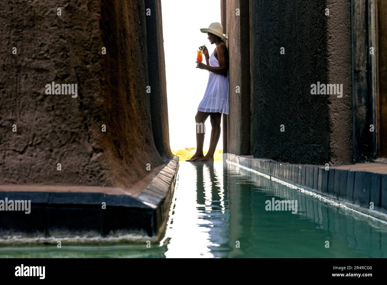 Modèle attrayant debout près de la piscine de réflexion à Onguma le fort, Onguma Game Reserve, Namibie, Afrique Banque D'Images