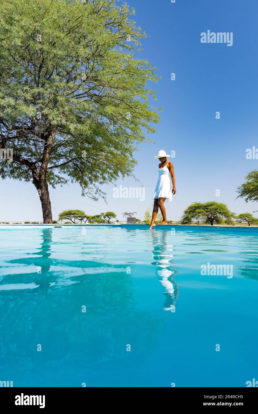 Femme en sundress blanche debout à côté de la piscine à Onguma le fort, Onguma Game Reserve, Namibie, Afrique Banque D'Images